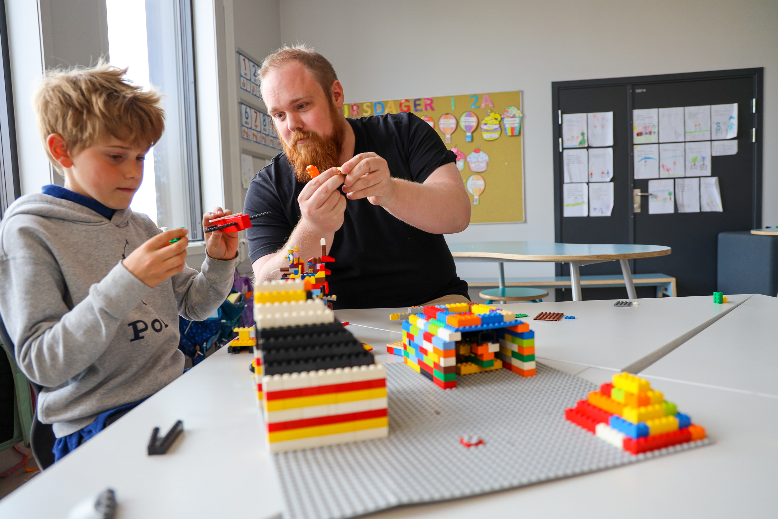 Gutt og ansatt bygger lego i klasserom.