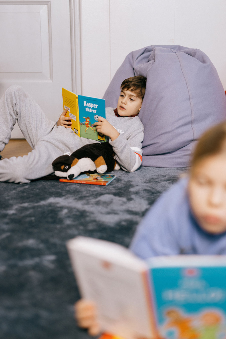 et barn som sitter på gulvet og leser en bok