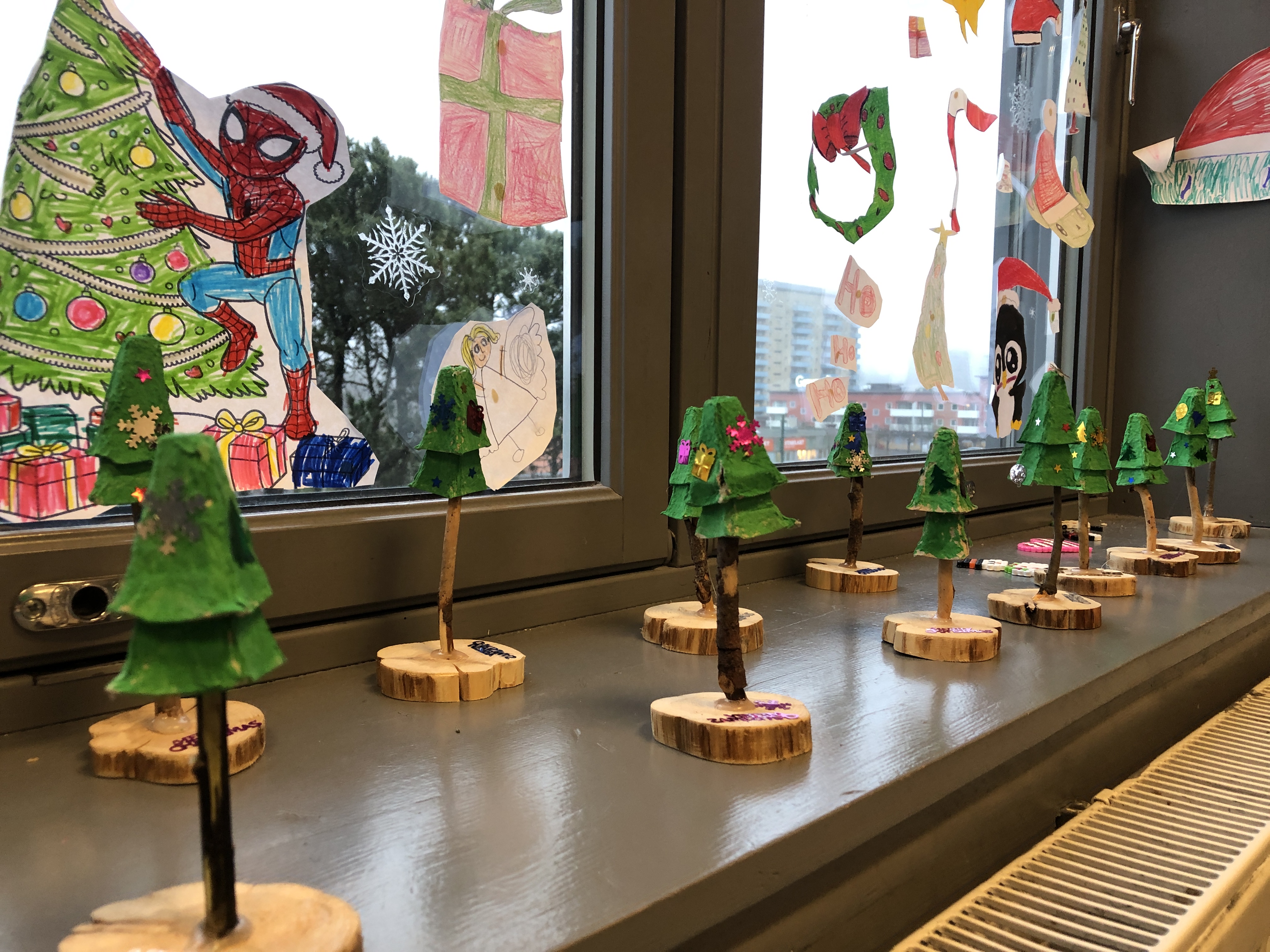 en gruppe små trær i et rom med et stort vindu