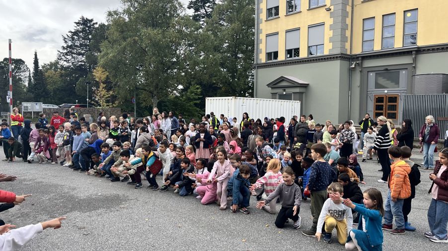 en gruppe mennesker som sitter på bakken utenfor